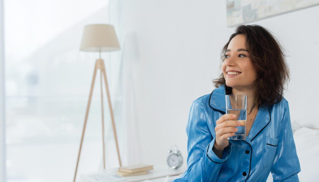 Happy young woman holding a glass of water